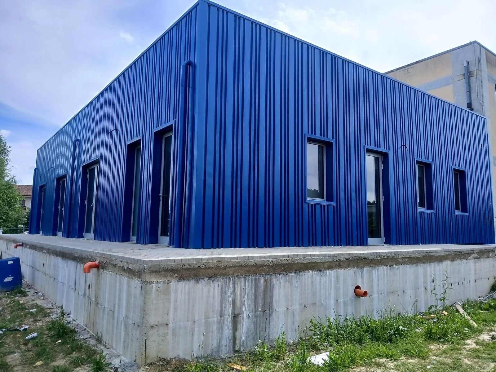 Facciata rivestita in lamiera grecata blu posata in verticale, con serramenti