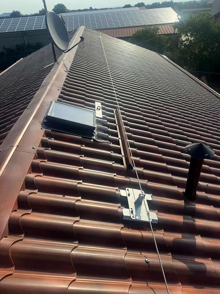 Linea vita con ancoraggio su una copertura in tegole, con finestra da tetto e comignolo